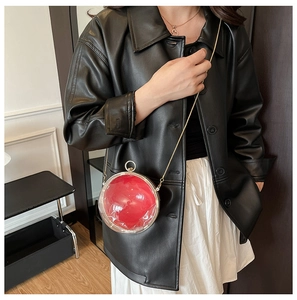 Détail d'une pochette sphérique rouge en acrylique avec chaîne dorée et coque claire