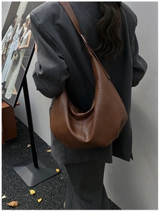 Détail du sac hobo marron foncé en cuir texturé porté à l'épaule par un mannequin de dos