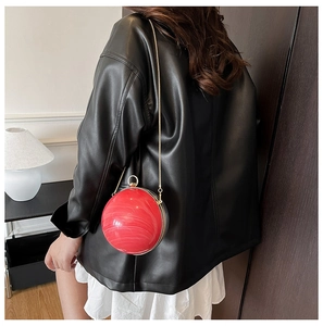 Détail d'une pochette sphérique en acrylique rouge avec texture marbre et chaîne dorée