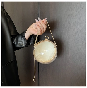 Détail d'une minaudière sphérique en acrylique perlé avec poignée anneau doré et chaîne