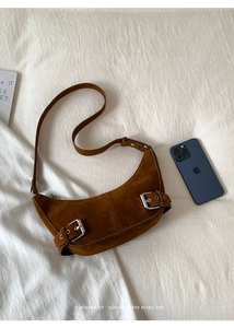 Top view of retro brown suede hobo bag with silver buckles on white linen fabric