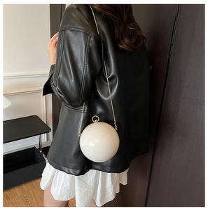 Détail du sac de soirée sphérique blanc crème avec chaîne dorée et fermoir anneau