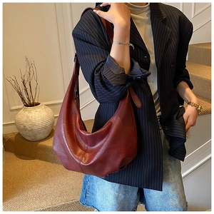 Sac à bandoulière bordeaux en cuir grainé porté avec une tenue de ville chic