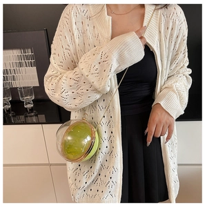 Détail de la pochette boule en acrylique avec intérieur vert et chaîne dorée sur modèle