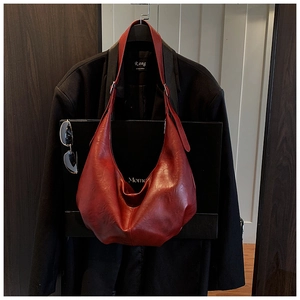 Détail d'un sac Hobo rouge foncé avec bandoulière réglable et texture cuir vintage