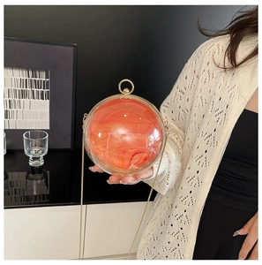 Détail du sac de soirée sphérique en acrylique transparent et orange avec poignée dorée