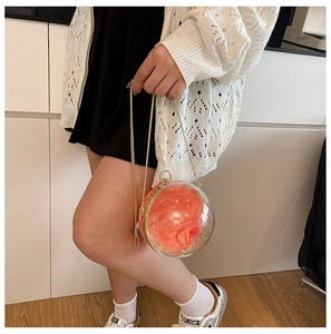 Vue détaillée du sac boule en acrylique contenant une rose orange avec chaîne dorée