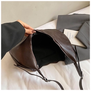 Gros plan d'un grand sac marron foncé montrant l'intérieur spacieux et le zip argenté