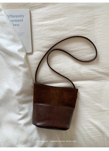 Detail of retro brown patchwork bucket bag with matte texture and slim shoulder strap