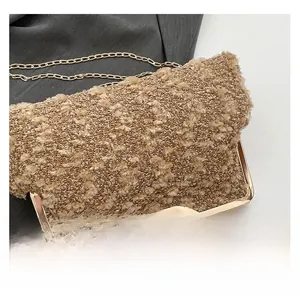 Detail of khaki textured fabric and golden metal handle of a stylish evening clutch bag