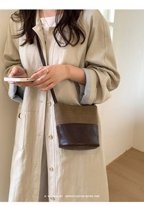 Gros plan sur un sac seau rétro bicolore minimaliste avec un trench-coat beige chic