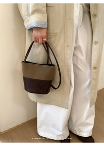 Close-up of minimalist retro bucket bag in olive green and dark brown leather contrast