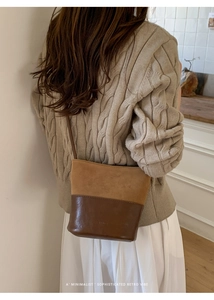 Dettaglio della borsa a secchiello retrò in pelle marrone e maglione in maglia a trecce