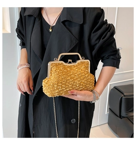 Close-up of a gold evening bag featuring a kiss lock clasp and metal chain handle