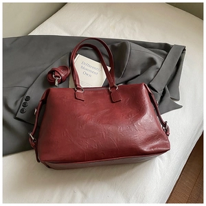 Detail of burgundy textured leather tote bag with sturdy handles and detachable shoulder strap