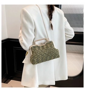 Close-up of grass green textured handbag with gold frame and chain on white blazer