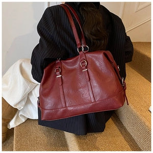 Detail view of large dark red leather tote bag with silver metal ring straps on model