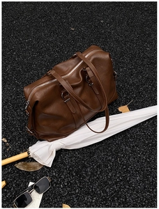 Detailed macro view of brown lychee grain leather travel bag with silver metal zippers