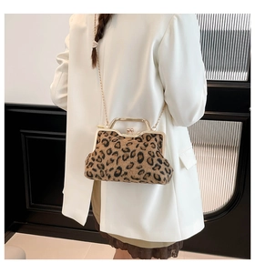 Detail of leopard print crossbody bag with gold metal handle and chain strap on a white blazer