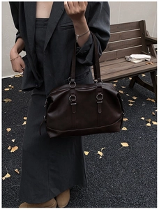 Outdoor model shot showing the dark brown leather Boston travel bag in a casual setting