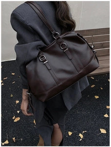Detail of dark brown leather tote bag with silver rings on an autumn park bench