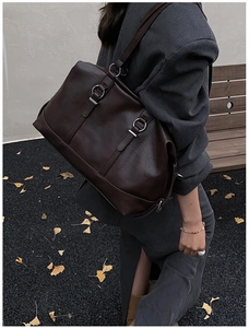 Detail of deep brown faux leather travel tote bag with silver metal rings and shoulder strap