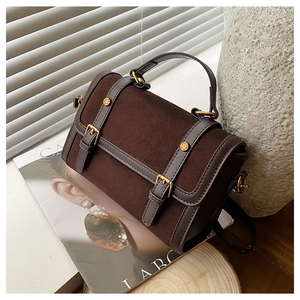 Détail du sac messager en daim marron avec boucles dorées et poignée élégante