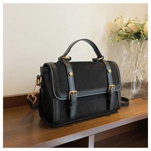 Détail du sac bandoulière noir avec finition mate et boucles dorées élégantes