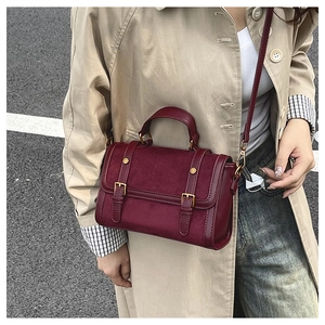 Détail du sac Boston en daim bordeaux avec boucles dorées vintage et finitions en cuir