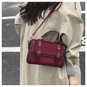 Détail du sac messager bordeaux en cuir givré avec boucles dorées et poignée renforcée