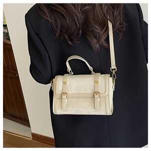 Vue détaillée d'un sac messager beige mat porté sur un blazer noir élégant et moderne