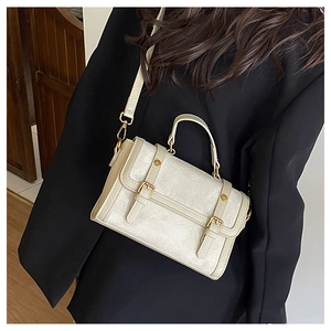 Détail du sac messager blanc cassé avec boucles dorées et bandoulière en cuir ajustable