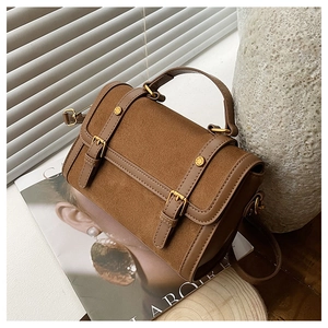 Détails de la texture du sac en daim marron vintage et des boucles métalliques dorées
