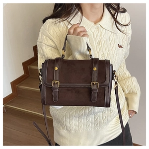 Détail du sac messager marron vintage en daim mat avec des boucles métalliques dorées
