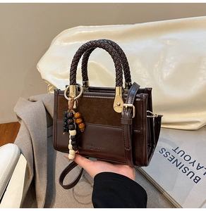 Detail of dark brown leather handbag with woven circular handle and tassel charm