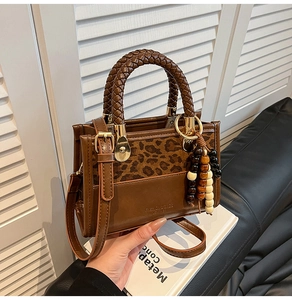 Detail of leopard print panel handbag with woven handle and beaded charm accessory