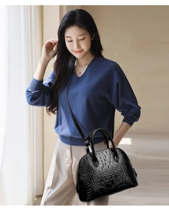 Sac à main noir motif crocodile porté par un mannequin montrant le style et la texture