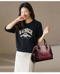 Détail du sac coquillage bordeaux à motif crocodile avec poignées sur mannequin