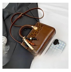 Detail of vintage brown leather bag with leopard print accent and beaded tassel charm