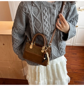 Detail of vintage brown crossbody bag with woven handle and beaded tassel on model