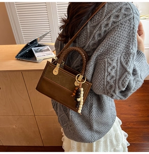 Detail of retro brown leather bag featuring hand-woven rope handle and wooden bead charms
