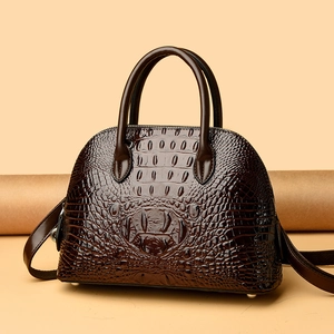 Détail d'un sac coquille marron foncé à motif crocodile avec finition brillante et clous