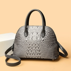 Détail du sac à main coquille gris motif crocodile avec poignées noires et pieds en métal