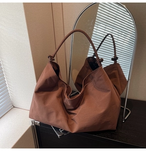 Detail of dark brown suede tote bag with decorative beads on the shoulder strap