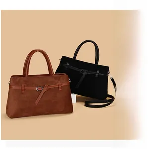 Detail of matte suede tote bag in brown and black with leather straps and metal buckles