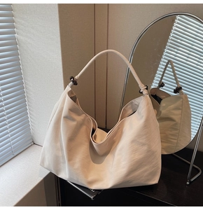 Detail of off-white hobo bag showing textured leather and dark brown bead on strap