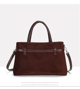 Detail of dark brown matte suede tote bag showing leather strap and metal hardware