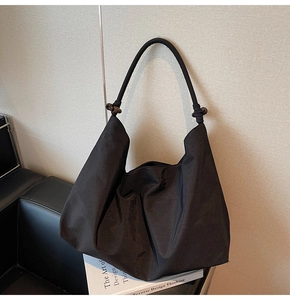 Artistic black canvas tote bag detail featuring large capacity folds and wooden bead decor