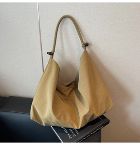 Detail of canvas shoulder bag featuring textured fabric and dark wooden bead strap accents