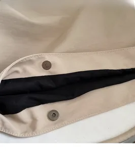Close-up of magnetic snap closure on khaki fabric tote with neat stitching detail
